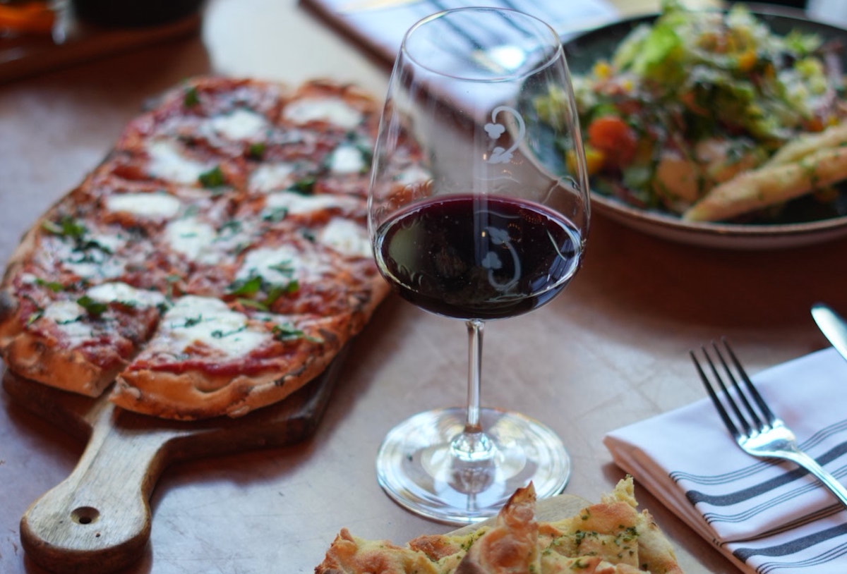 Crú Food & Wine Bar pairs artisan pizzas, fresh salads, and an extensive wine selection for an elevated airport dining experience. | Photo by Crú Food & Wine Bar