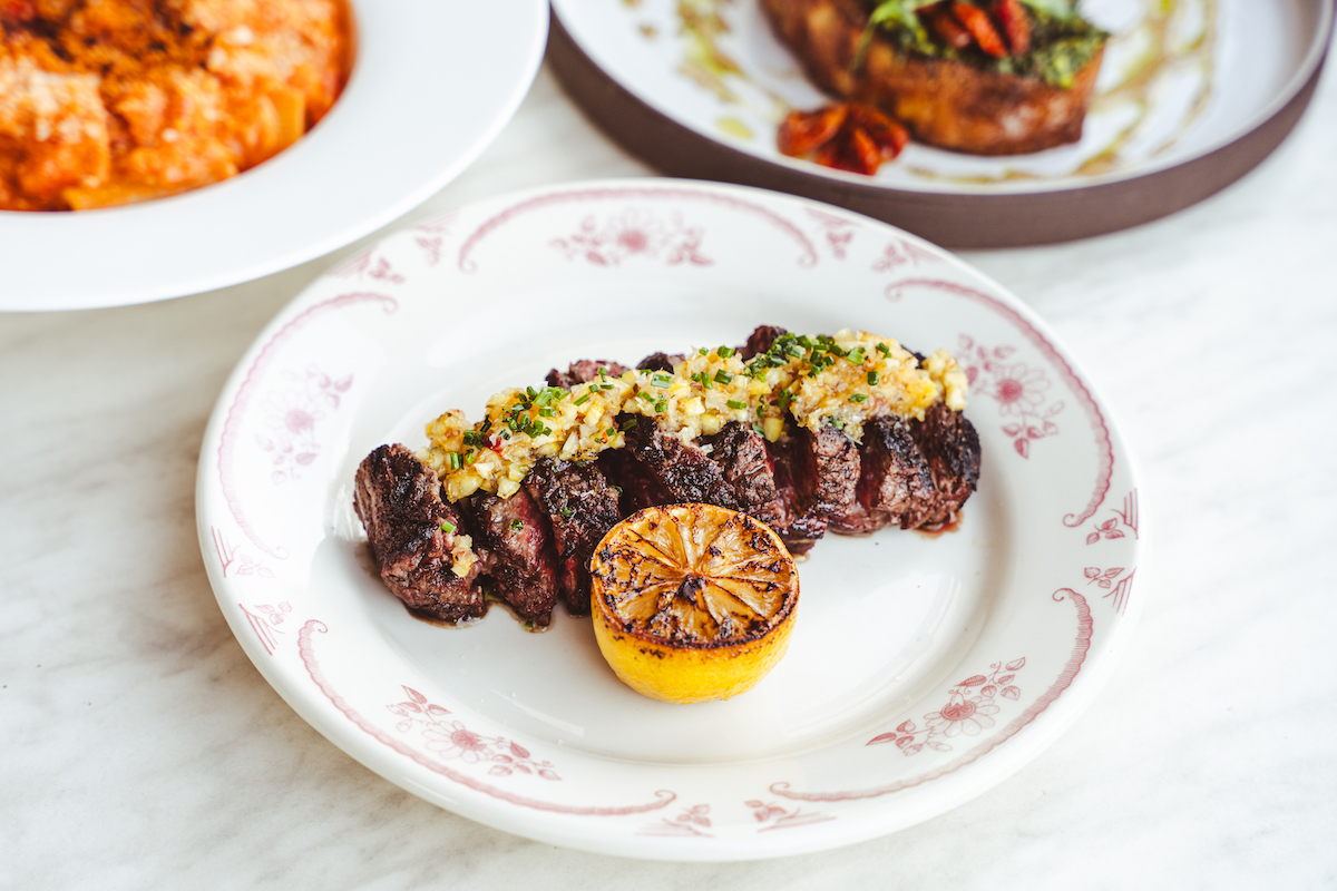 A wood-fired steak finished with roasted garlic and herbs highlights Luella’s Italian steakhouse menu. | Photo by Luella