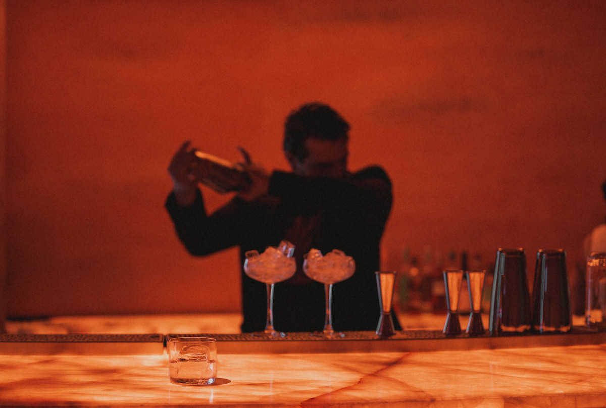 A bartender prepares cocktails behind the glowing bar at La Cueva, the slot canyon-inspired mezcal lounge hidden inside Ponce City Market’s Central Food Hall. | Photo by Lauren Lynn
