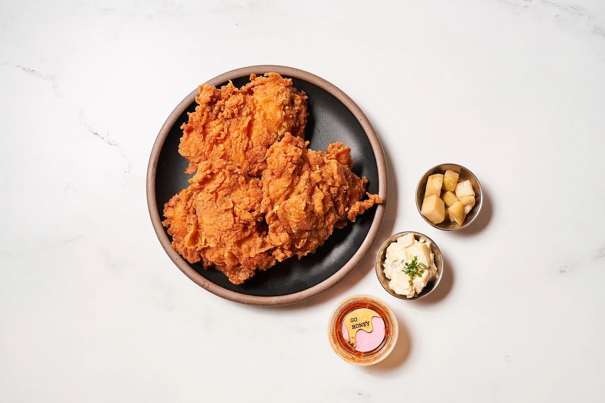 Perfectly crispy chicken with banchan. | Photo courtesy of KJUN