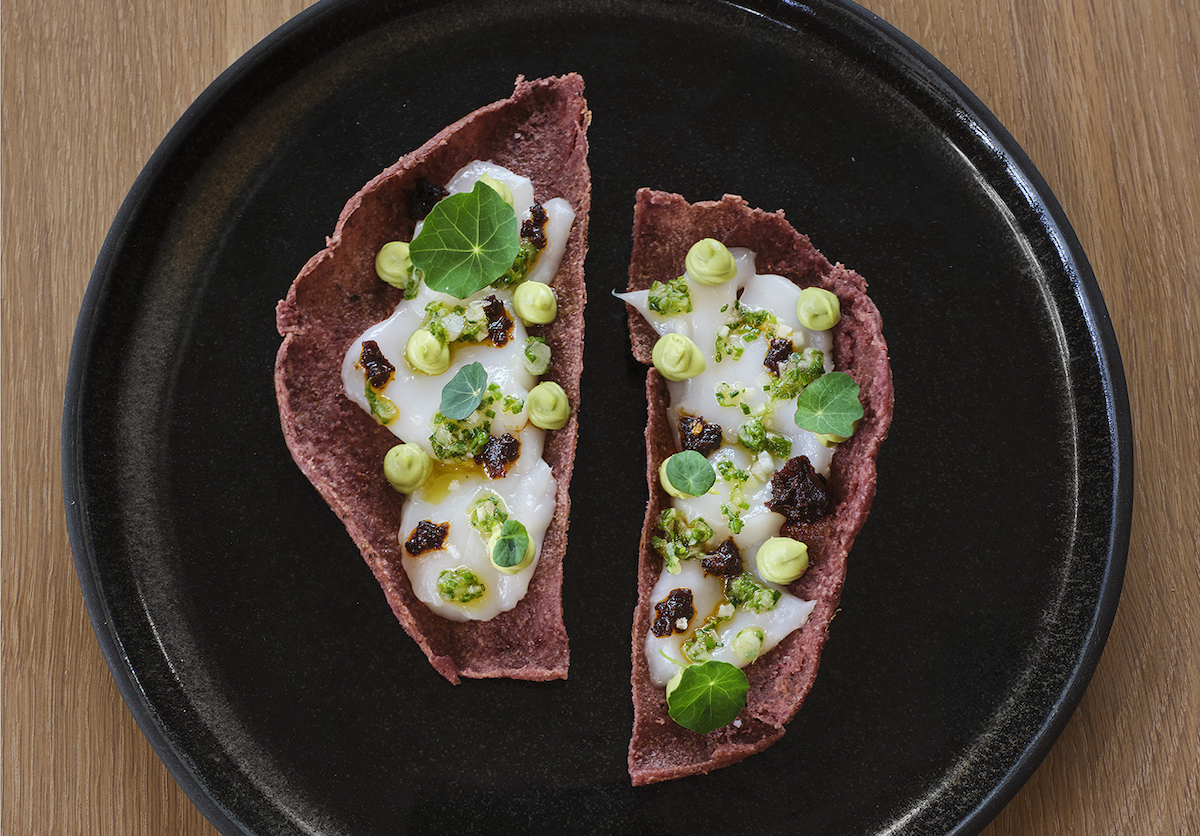 Oloyo_TosadadeCallo_PhotobtElizabeth Lavin - DiningOut The Tostada de Callo at Olōyō layers fresh scallops over a blue corn tostada with avocado purée, salsa macha, herbs, and borage. | Photo by Elizabeth Lavin
