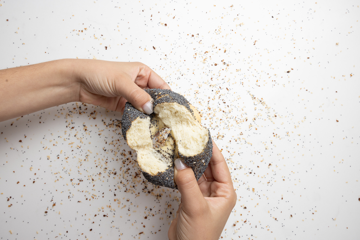 A warm poppy seed bagel is pulled apart to reveal its fluffy interior at PopUp Bagels. | Photo by Alex Stein