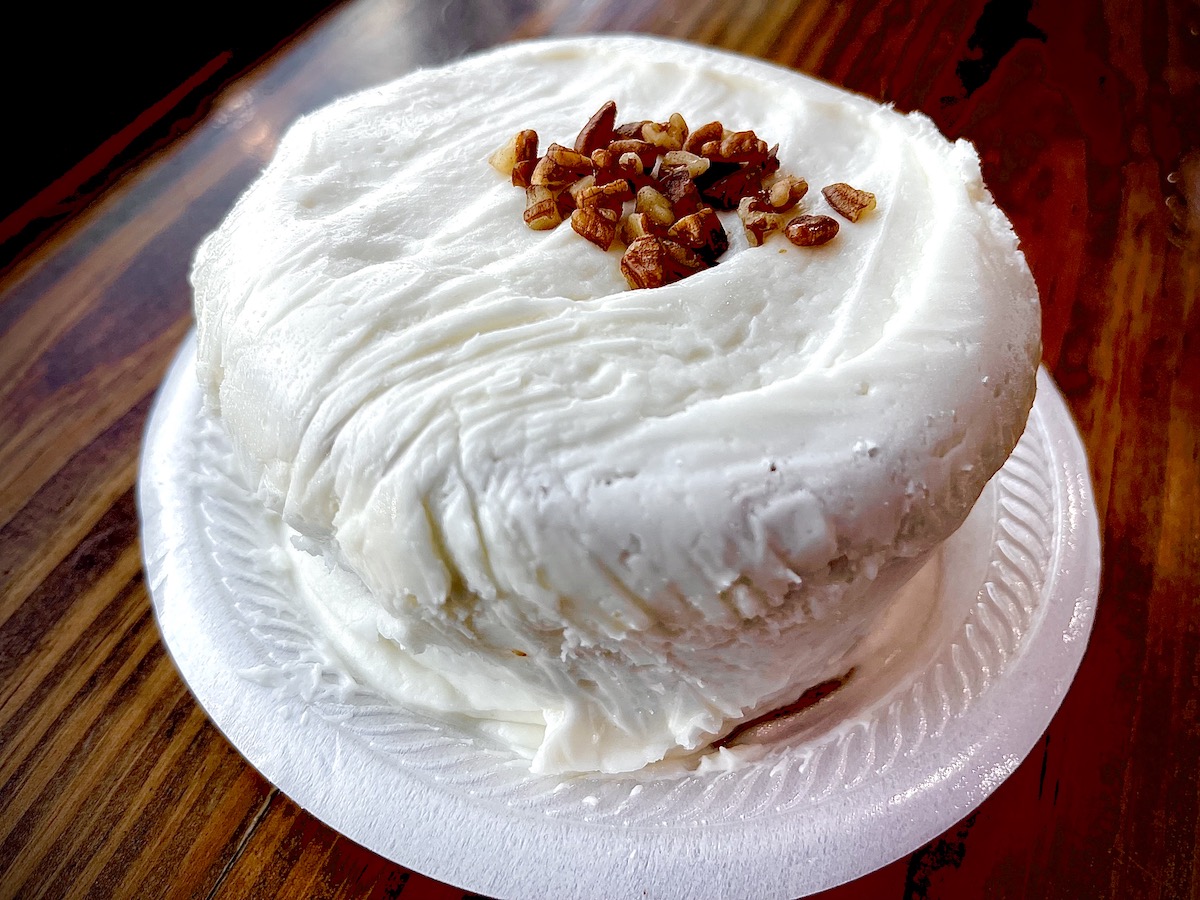 A towering slice of Ray’s Real Pit BBQ Shack cake arrives generously frosted and big enough to share—though you may not want to. | Photo by Ray’s Real Pit BBQ Shack