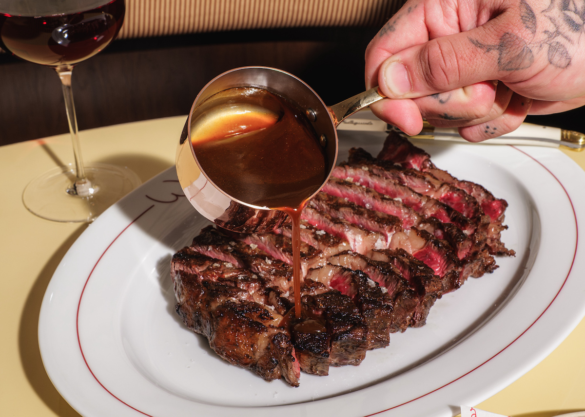 A server finishes Walkers’ wagyu ribeye with a rich jus during dinner service. | Photo by Dacoge Media