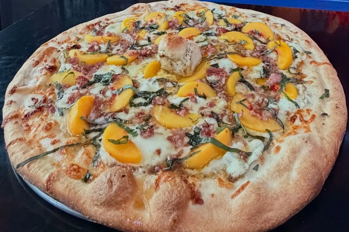 Catch one of the weekly specials like Mama’s Little Helper, with peach slices and bacon on a garlic slurry base with ricotta, mozzarella, onions, and basil. | Photo courtesy of Night Owl Pizza & Drinks