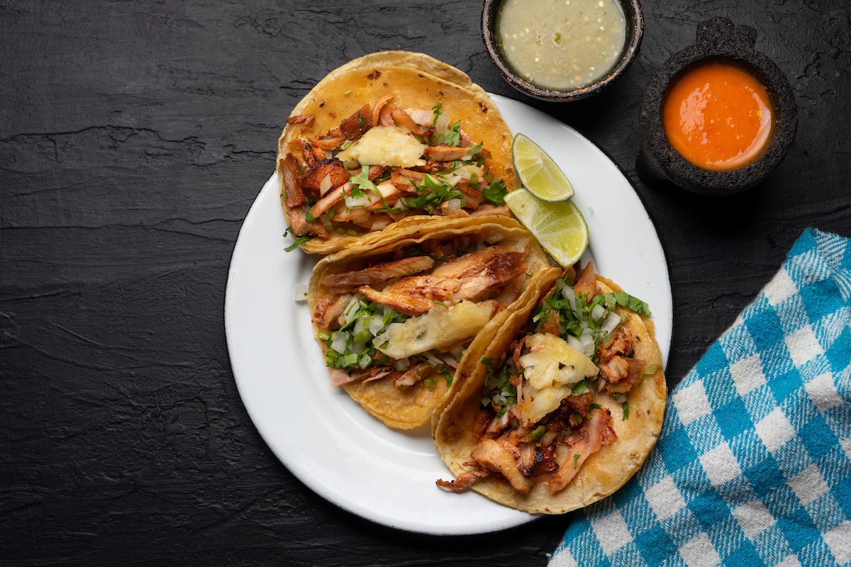 Pork tacos called al pastor with pineapple on dark background. Traditional mexican tacos