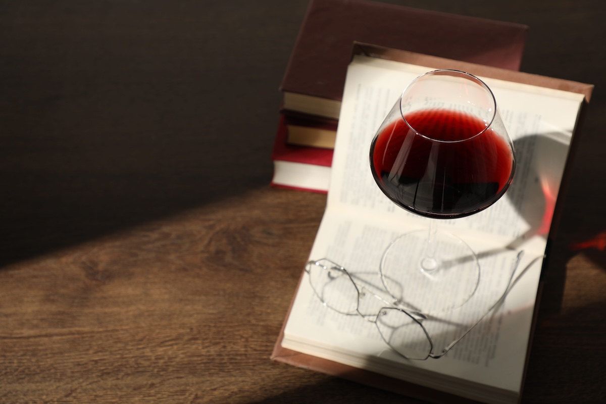 Glass of wine, books and glasses on wooden table. Space for text nyc bookstore