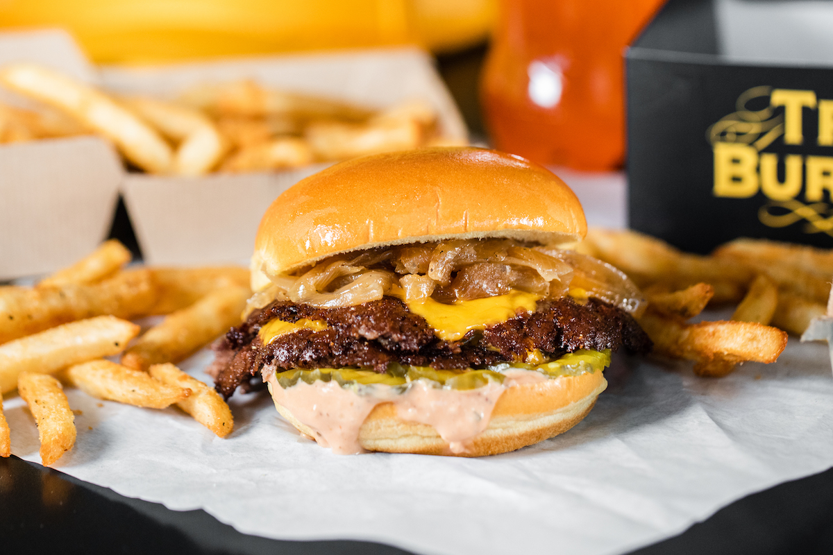 The OG Trill Burger—stacked with two smashed beef patties, American cheese, caramelized onions, pickles and Trill Sauce—will headline the menu at the new Rice University location. | Photo by Trill Burger