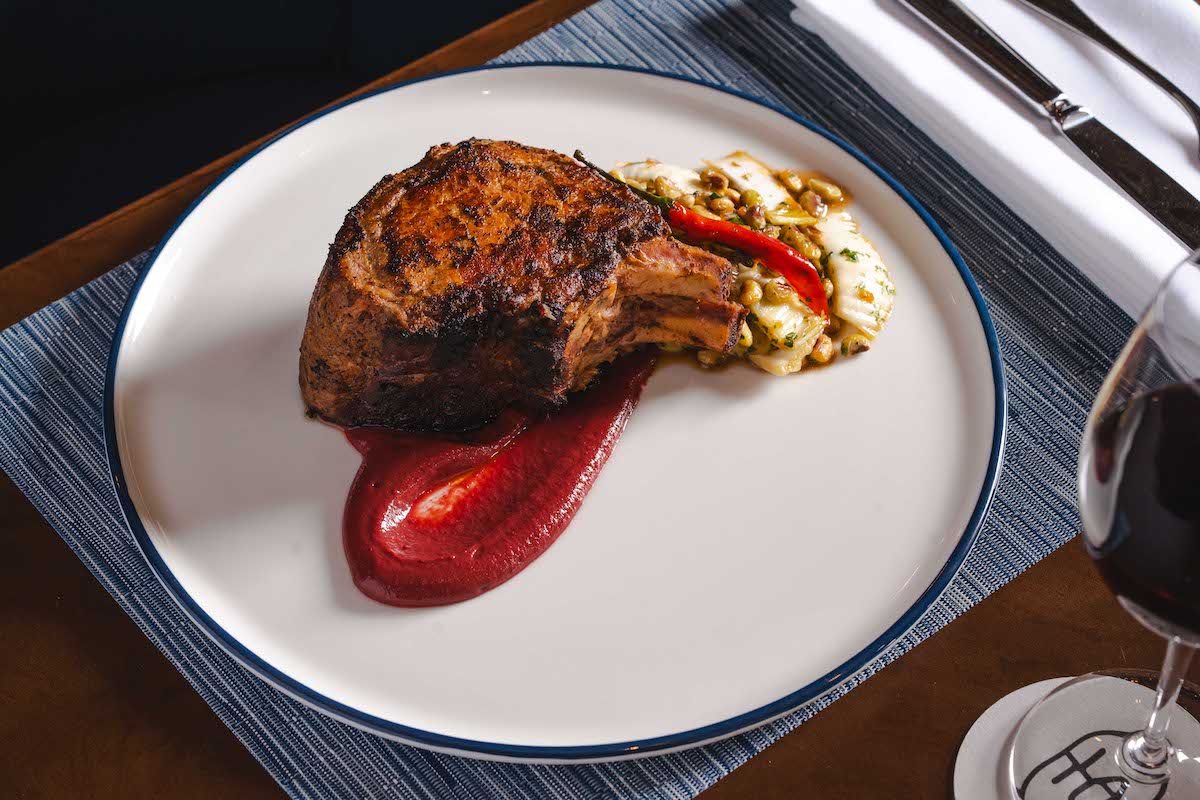 Latuli's double-cut pecan-smoked pork chop showcases Bryan Caswell's commitment to thoughtfully sourced Texas meats, paired with black-eyed peas, Napa cabbage, and cherry mustard. | Photo by Michael Anthony