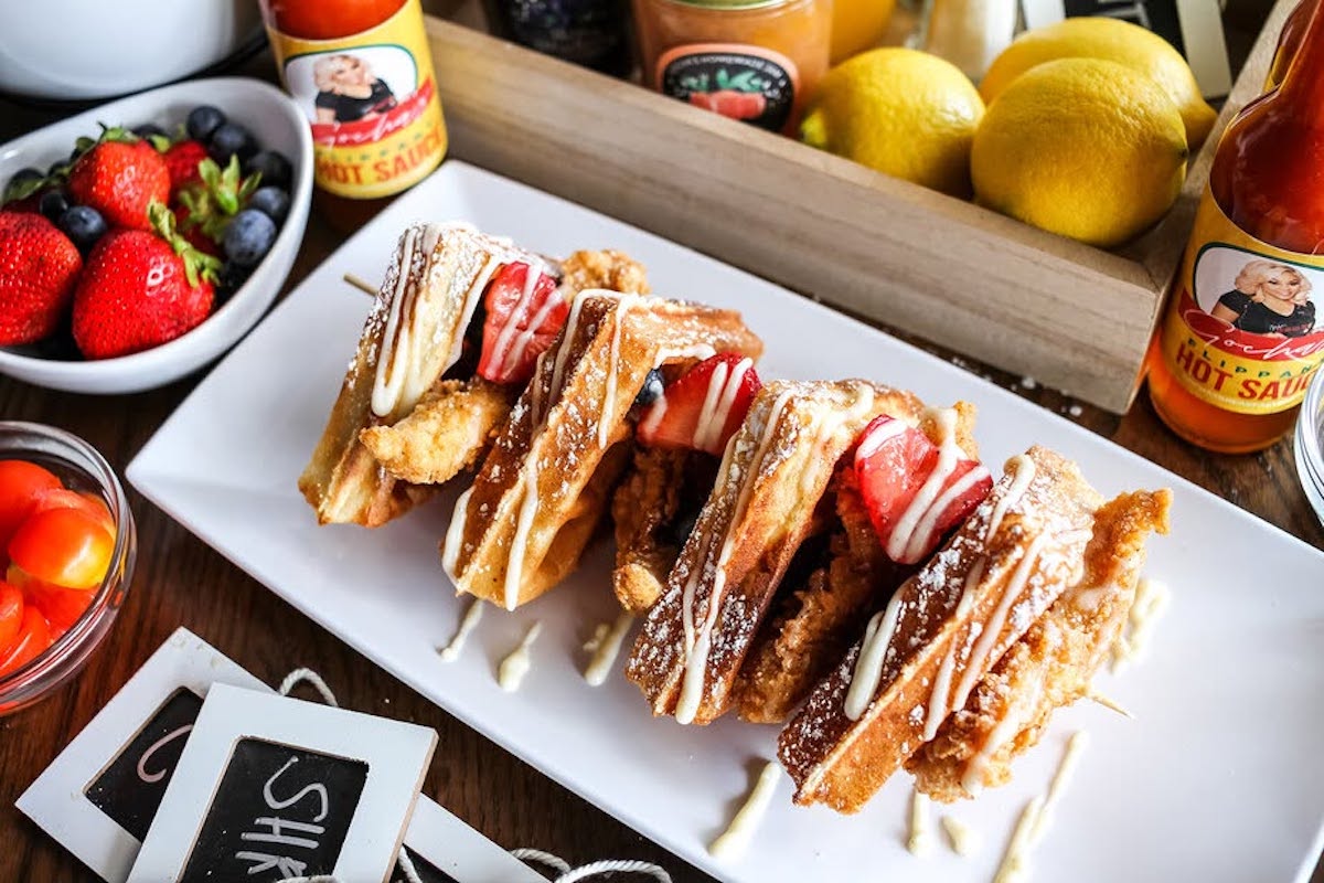 Gocha's signature chicken and waffles, topped with fresh strawberries and white chocolate drizzle. | Photo by Gocha's Breakfast Bar