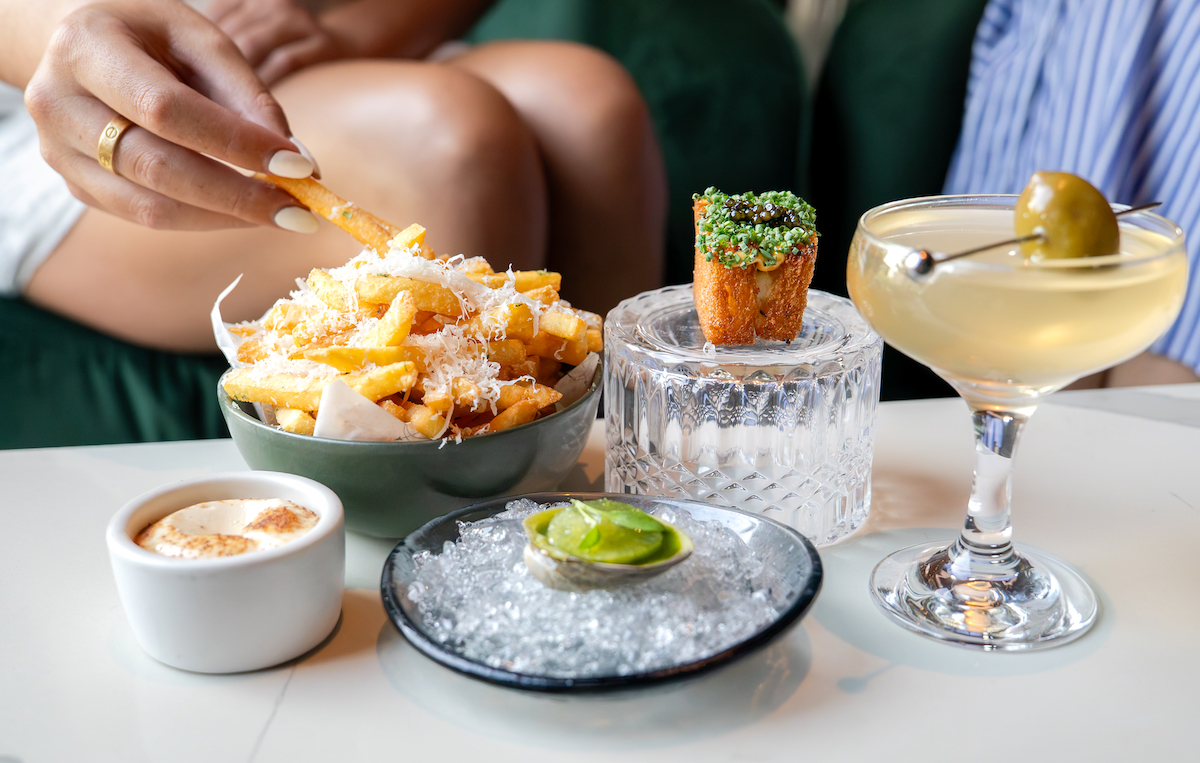 Meridian's "Girl Dinner" pairs indulgent bites like Parmesan fries, oysters, and caviar-topped snacks with a classic martini, offering a playful take on the viral trend. | Photo by Meridian