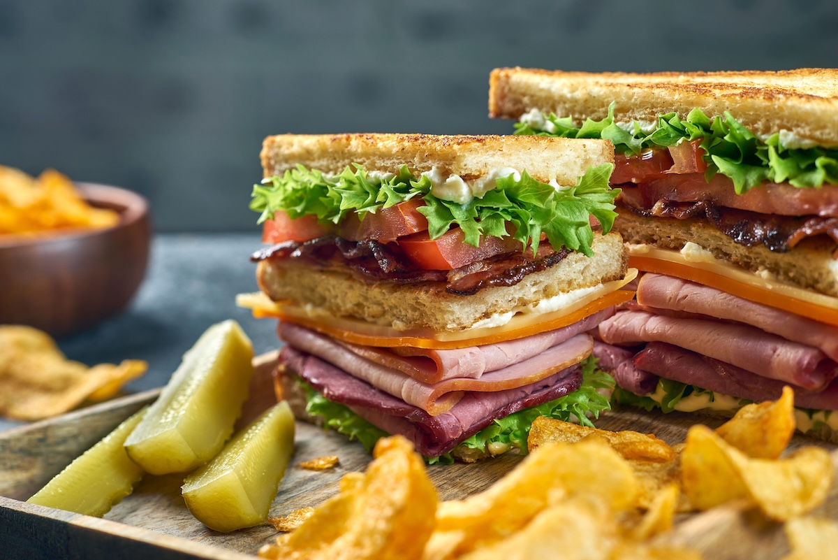 Pieces of club sandwich with potato chips on wooden tray phoenix sandwich deli