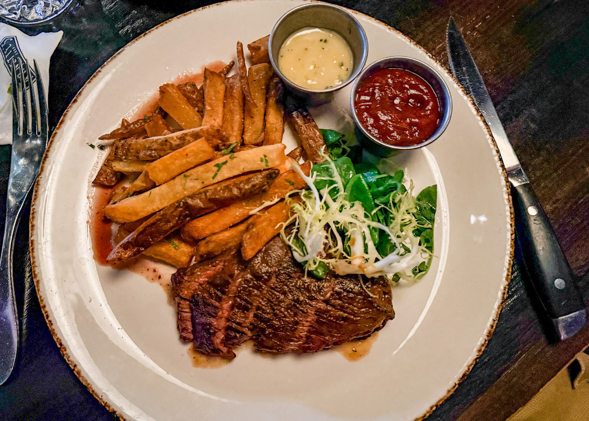 Steak frites at Arnette’s Chop Shop comes with a charred hanger steak, thick-cut fries, greens, and sauces on the side. | Photo by Sarah Bisacca