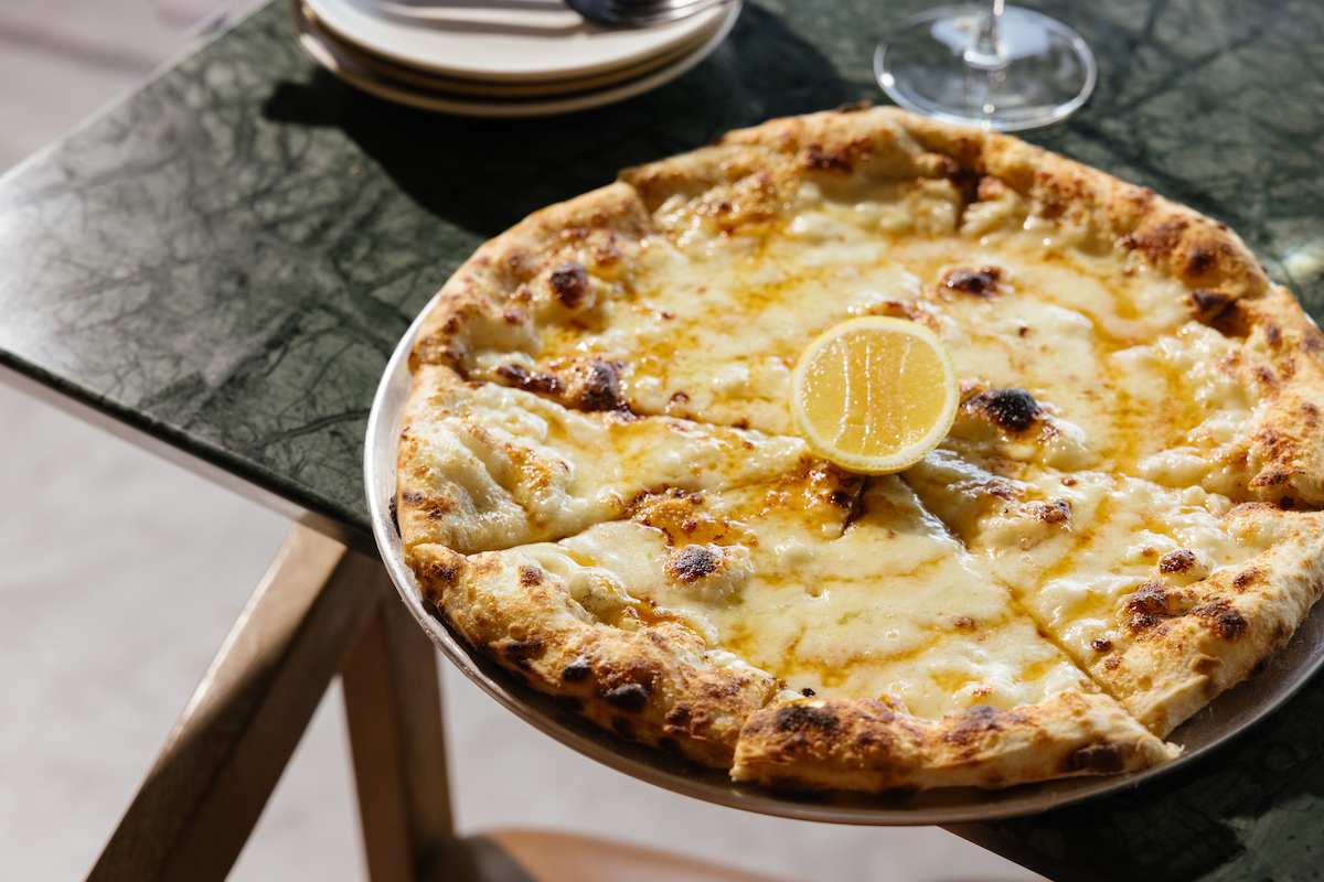 Élephante DAL - DiningOut Élephante’s Bianco pizza arrives bubbling from the oven with a charred crust and a bright squeeze of lemon. | Photo by Élephante