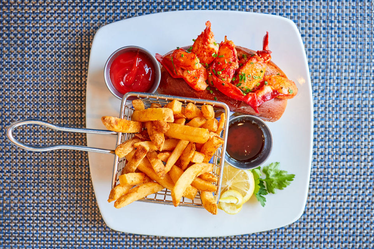 Big Bs Fish Joint - DiningOut Big B's Fish Joint serves its lobster roll with Maine lobster finished in brown butter and lemon on a toasted New England bun, alongside Old Bay-seasoned fries. | Photo by Big B's Fish Joint