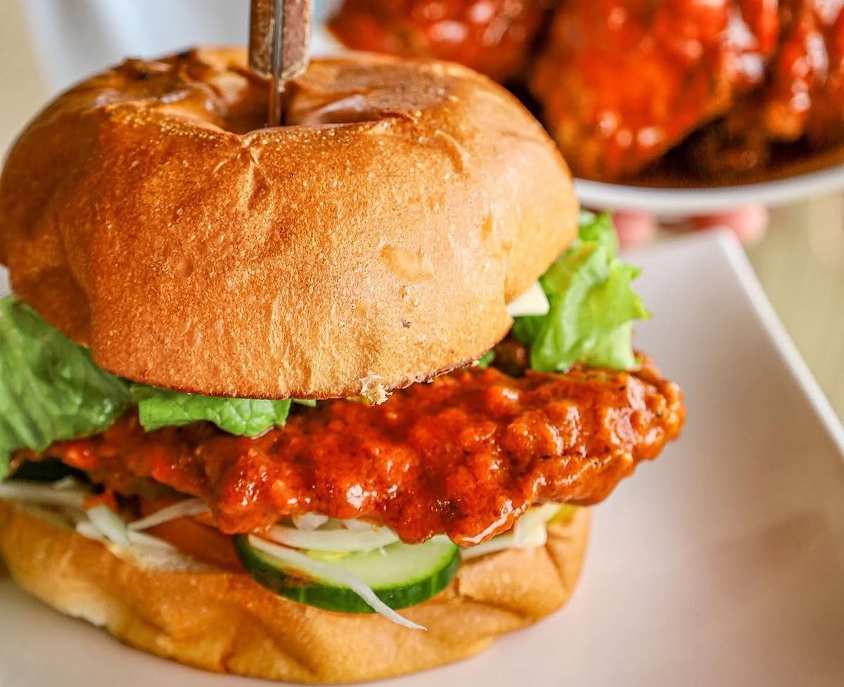 Nashville hot chicken gets a South Asian twist at Bismillah, where a crispy chicken sandwich comes slathered in a fiery, spice-packed sauce. | Photo by Bismillah Restaurant & Cafe