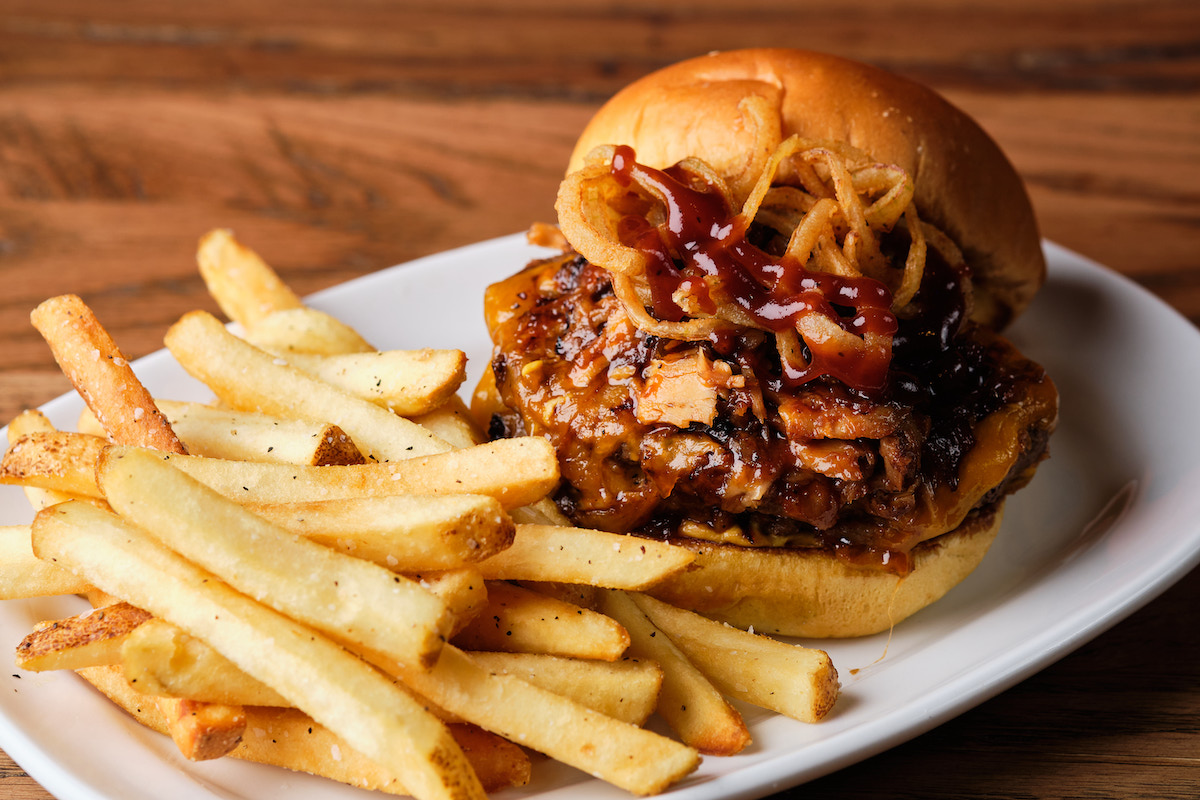 The new Bourbon Smokehouse Burger at HOBNOB Neighborhood Tavern is piled with bourbon barbecue pulled pork and bacon jam and served with fries. | Photo by HOBNOB Neighborhood Tavern