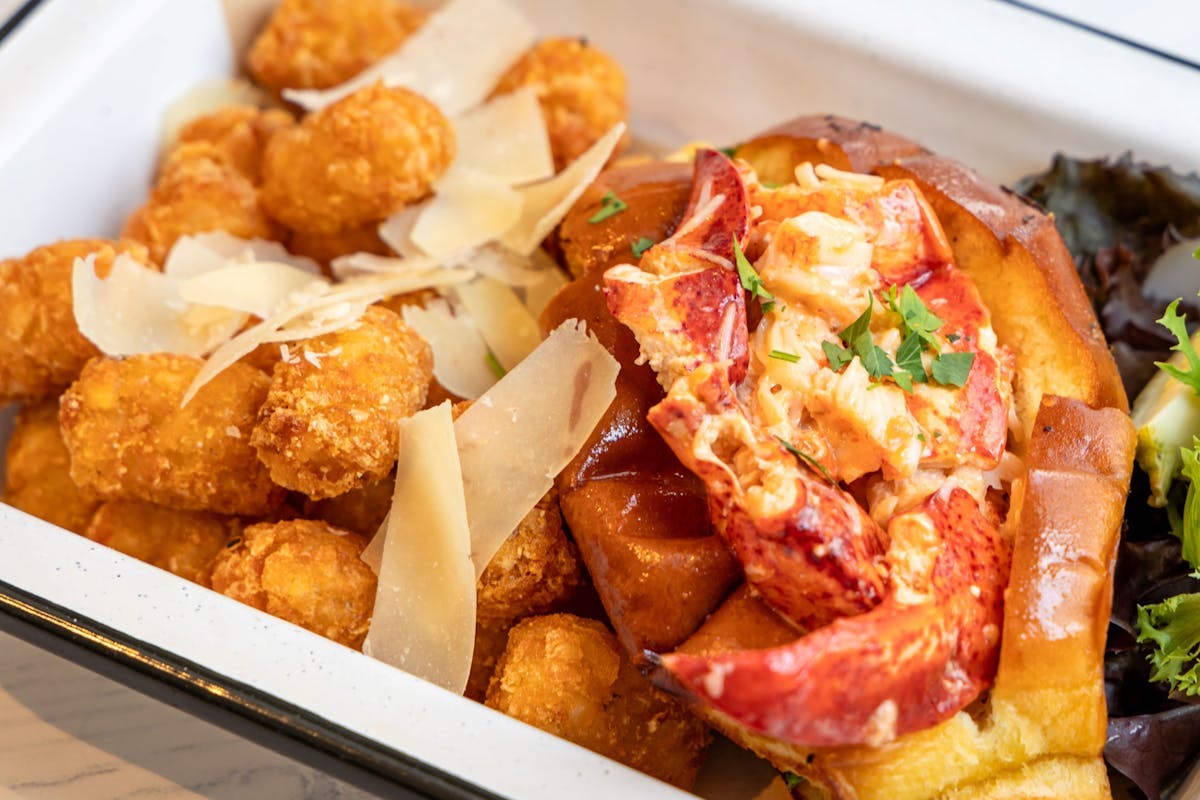 Brown Bag Seafood Co. - DiningOut Brown Bag Seafood Co.'s warm Connecticut-style lobster roll is served on a toasted bun with a side of crispy truffle-Parmesan tots. | Photo by Brown Bag Seafood Co.