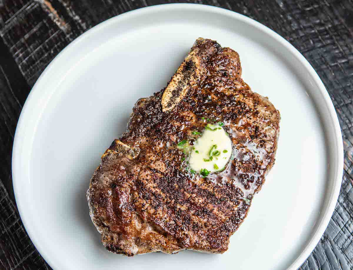 Cattle Shed - DiningOut Cattle Shed’s bone-in Kansas City strip is finished with a pat of herb butter. | Photo by Cattle Shed