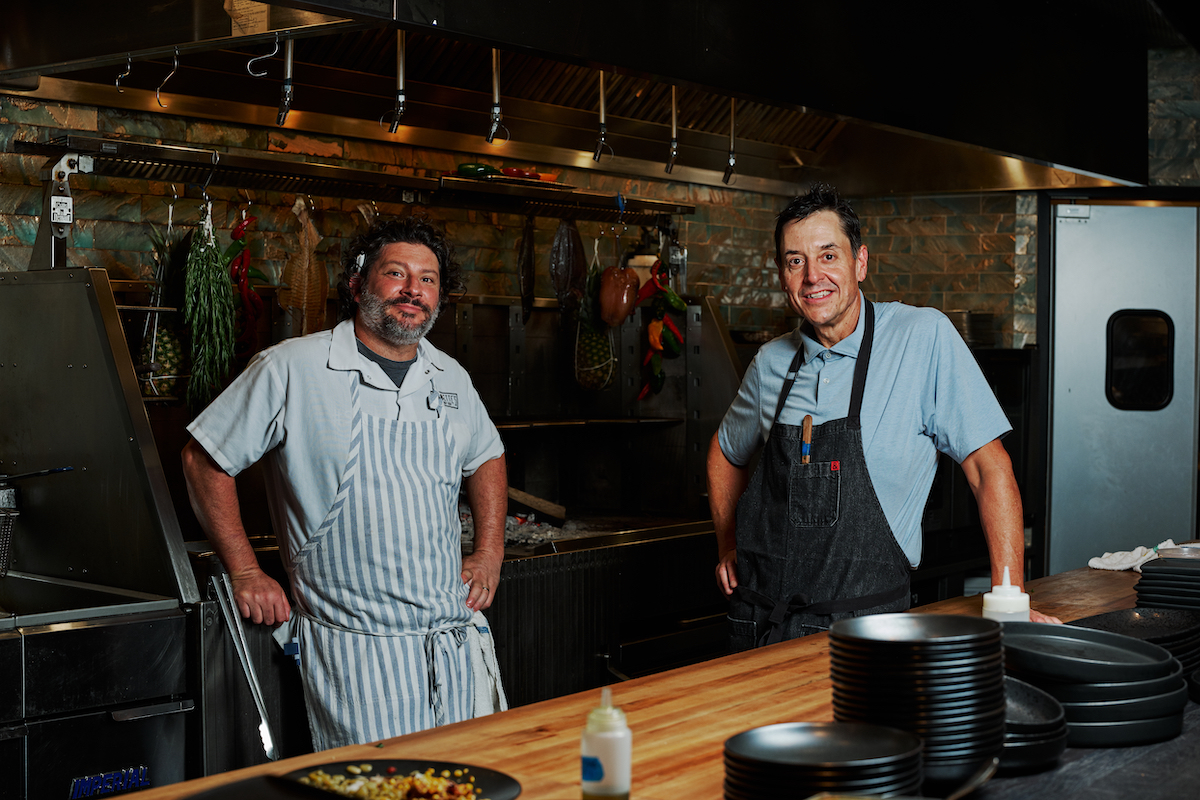 Chefs Stephen Herman and Matt Swickerath stand in front of Siren’s custom wood-burning range, the centerpiece of the Brookhaven seafood restaurant’s open kitchen. | Photo by Andrew Thomas Lee