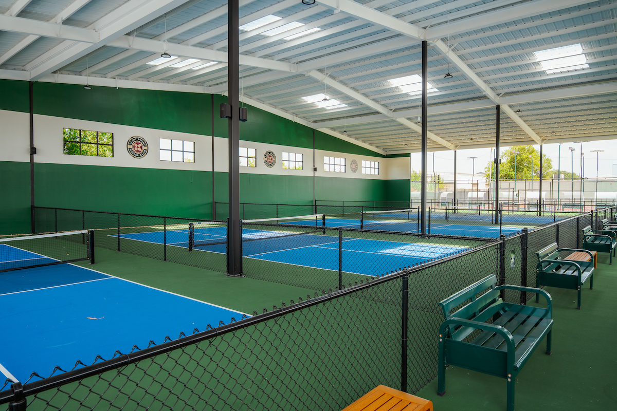 Covered pickleball courts with benches - DiningOut Long Point Social Club features 12 pickleball courts, including eight covered courts, plus four padel courts for league play, lessons and casual matches. | Photo by Hasan Yousef