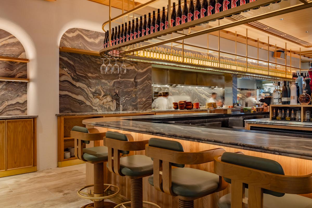 Élephante DAL - DiningOut Élephante Dallas pairs a dramatic marble bar with warm woods, sculptural details, and an overhead display of illuminated wine bottles. | Photo by Élephante