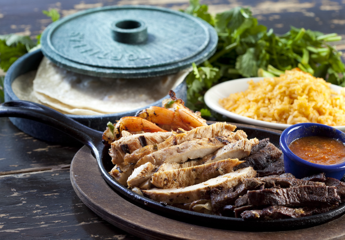A platter of beef, chicken, and shrimp fajitas is served with warm tortillas, Mexican rice, and salsa at Molina’s Cantina. | Photo by Julie Soefer