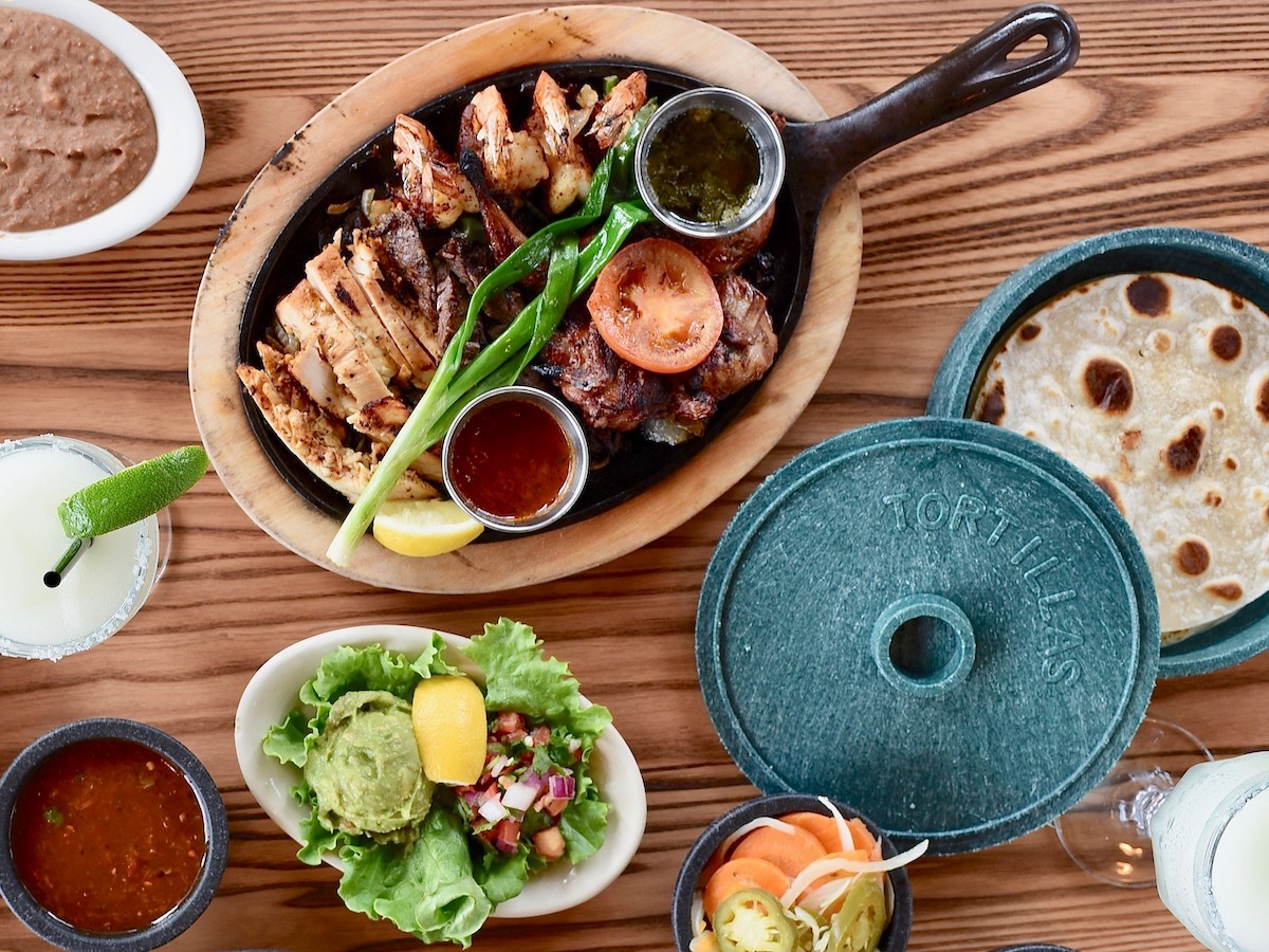 Beef, chicken, and shrimp fajitas come off the grill and are served with roasted vegetables, warm flour tortillas, guacamole, pico de gallo, and salsa. | Photo by Kimberly Park