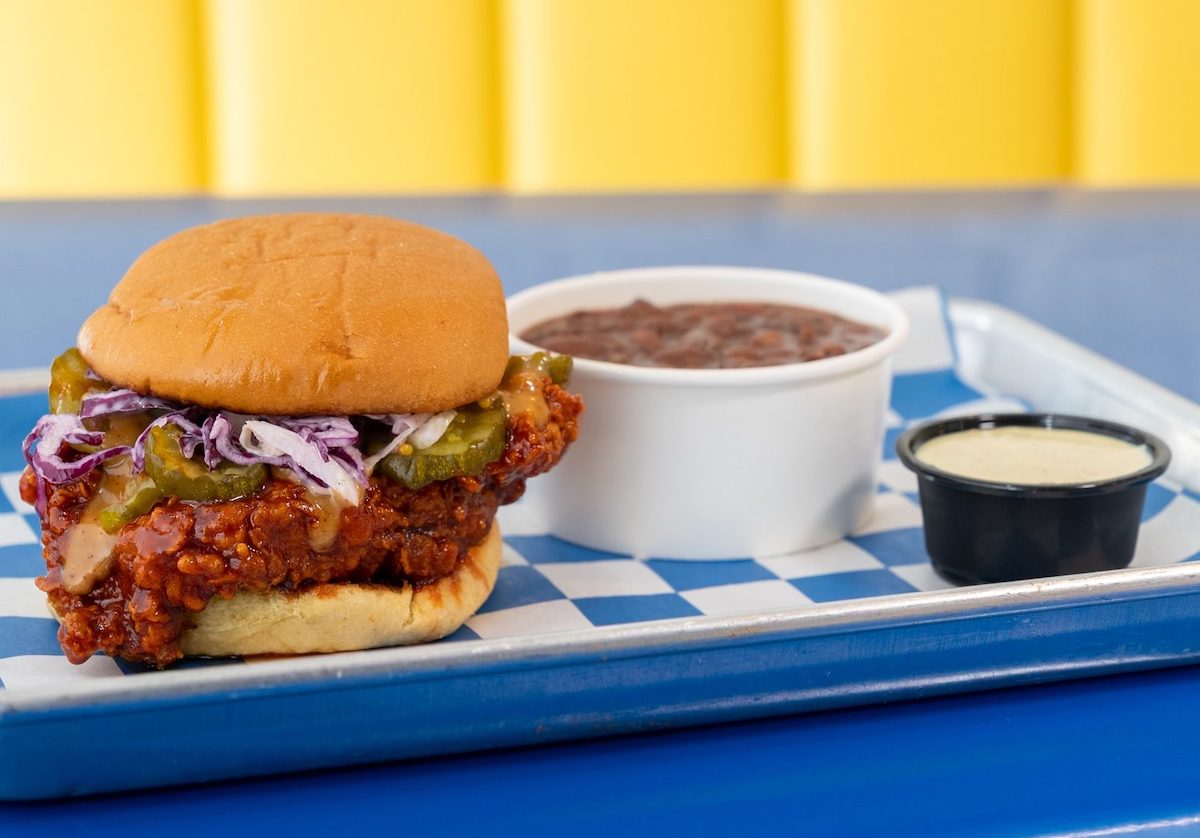Pepper Roost’s Flamin’ Rooster Chicken Sando pairs fiery hot chicken with pickles and ginger slaw on a buttery bun, with homemade rooster sauce. | Photo by Pepper Roost