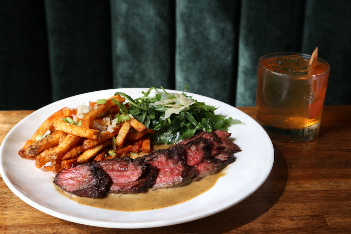 Rainbow Lodge’s September special is a grilled hanger steak with peppercorn sauce, arugula salad, and fries alongside a Texas Old Fashioned. | Photo by Paula Murphy
