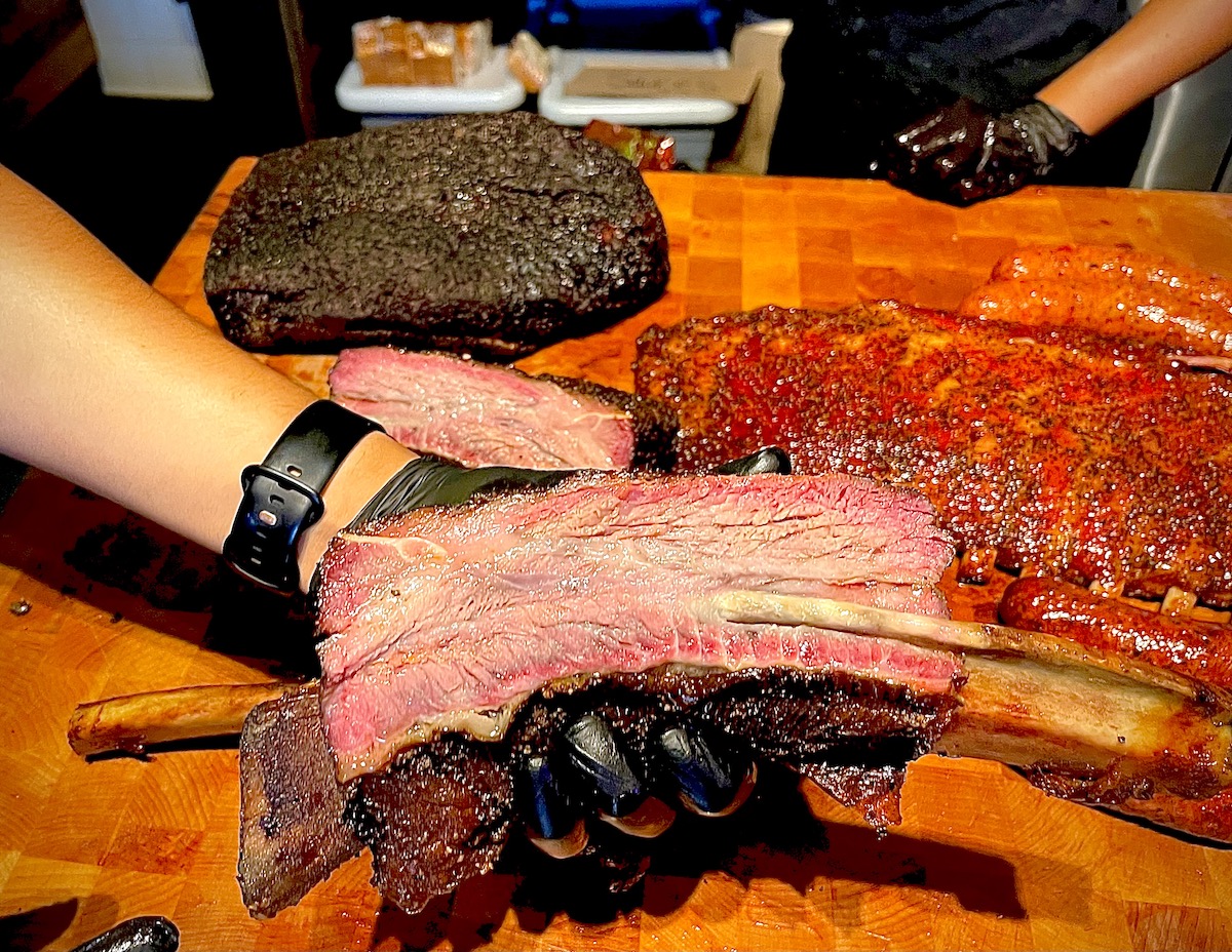 Terry Black's Barbecue HTX - DiningOut Terry Black’s massive “Dino” beef rib shows off a deeply smoked bark and rosy, tender interior. | Photo by Greg Morago