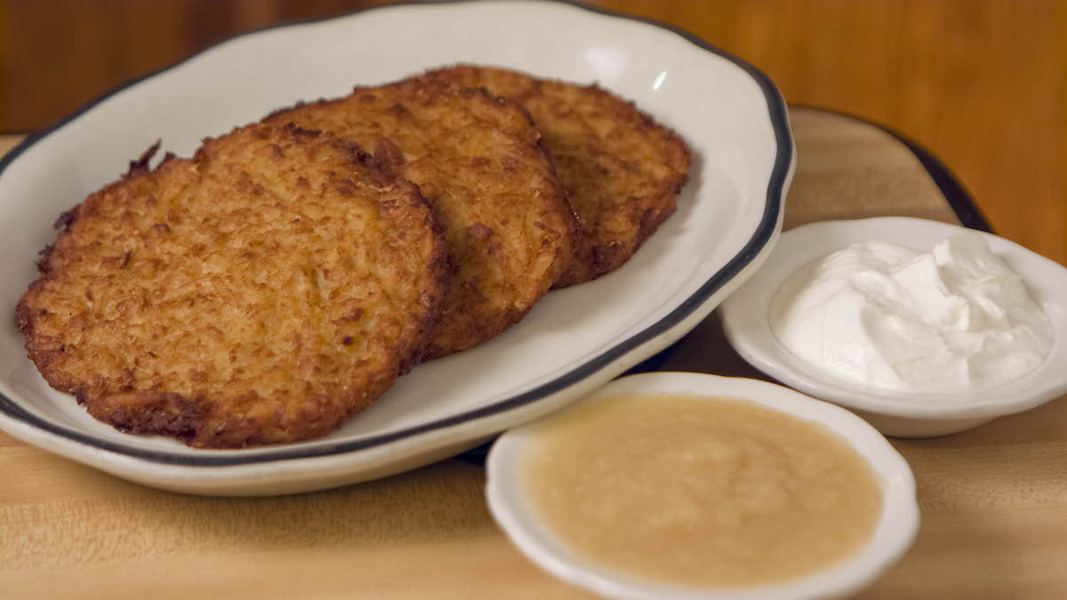 Golden potato latkes are served with sour cream and applesauce at Kenny & Ziggy’s. | Photo by Kenny & Ziggy's