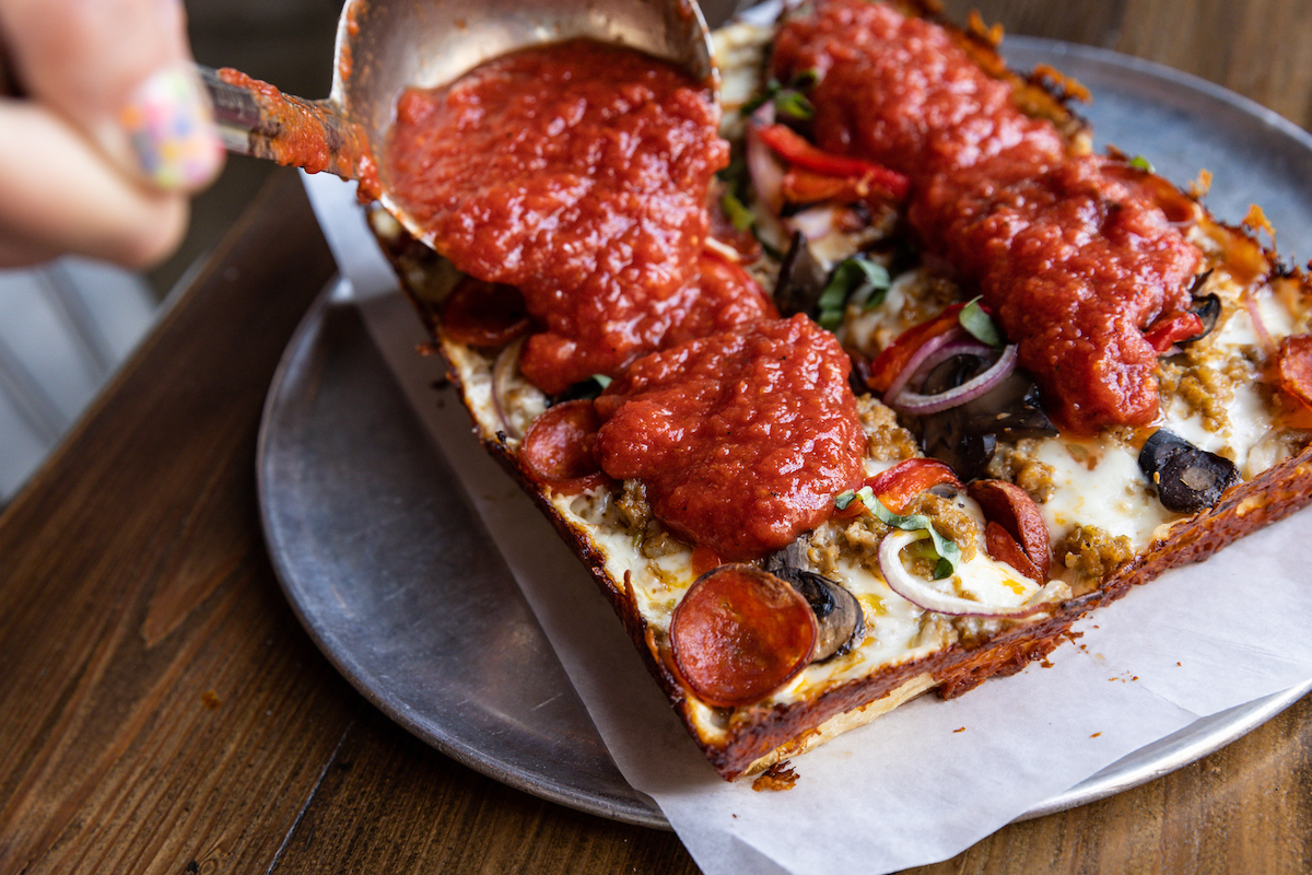 Pizaro’s Motor City Detroit-style pizza gets a generous finishing layer of red sauce. | Photo by Sergio Trevino