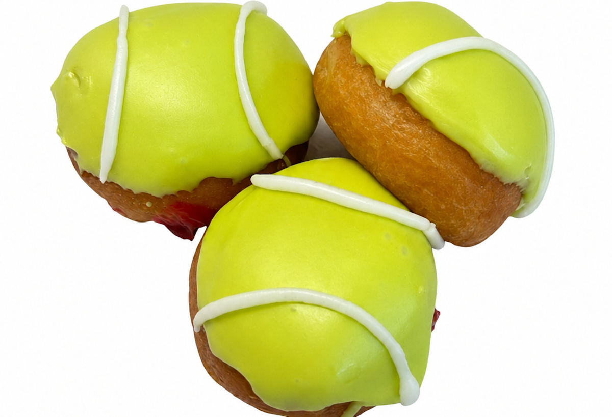 Three lime-yellow donuts with white icing drizzle arranged together on a white background.