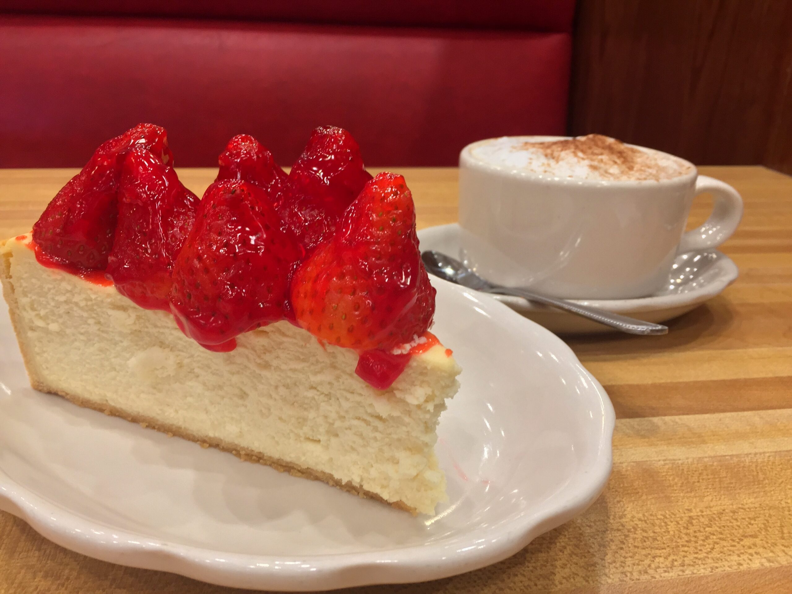 A towering slice of New York-style cheesecake crowned with glazed strawberries makes a fitting finish at Kenny & Ziggy’s. | Photo by Kenny & Ziggy's