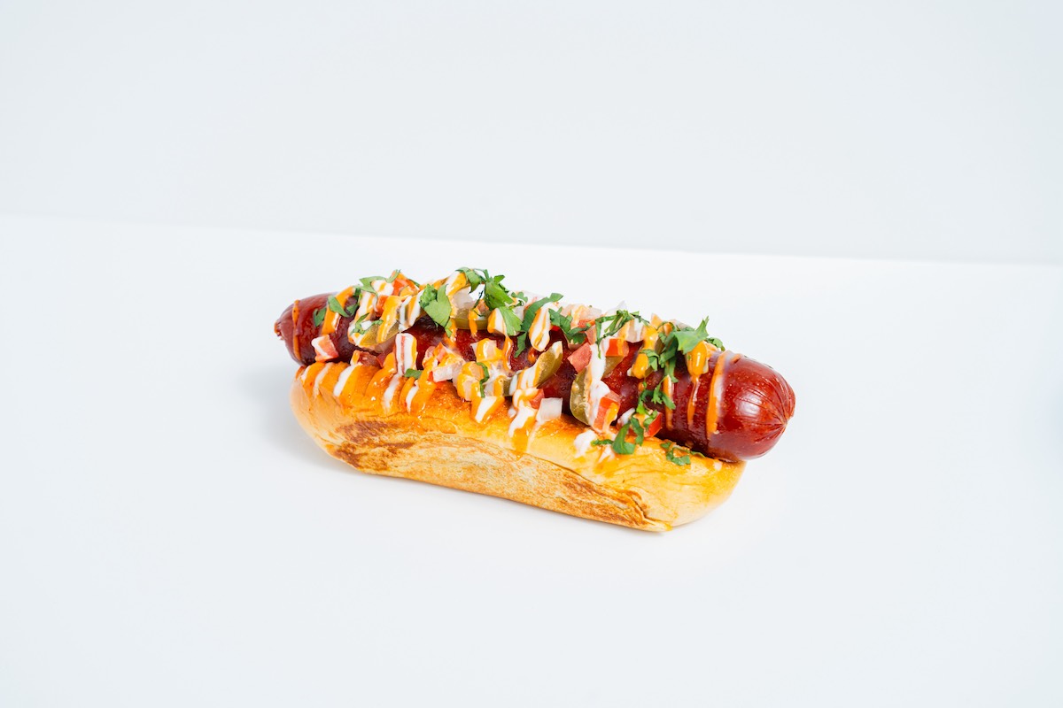 Buttermilk Baby Tex-Mex Dog - DiningOut Buttermilk Baby’s limited-time Tex-Mex Dog tops a wagyu beef hot dog with onions, tomatoes, pickled jalapeños, cilantro, and chipotle aioli. | Photo by Hasan Yousef