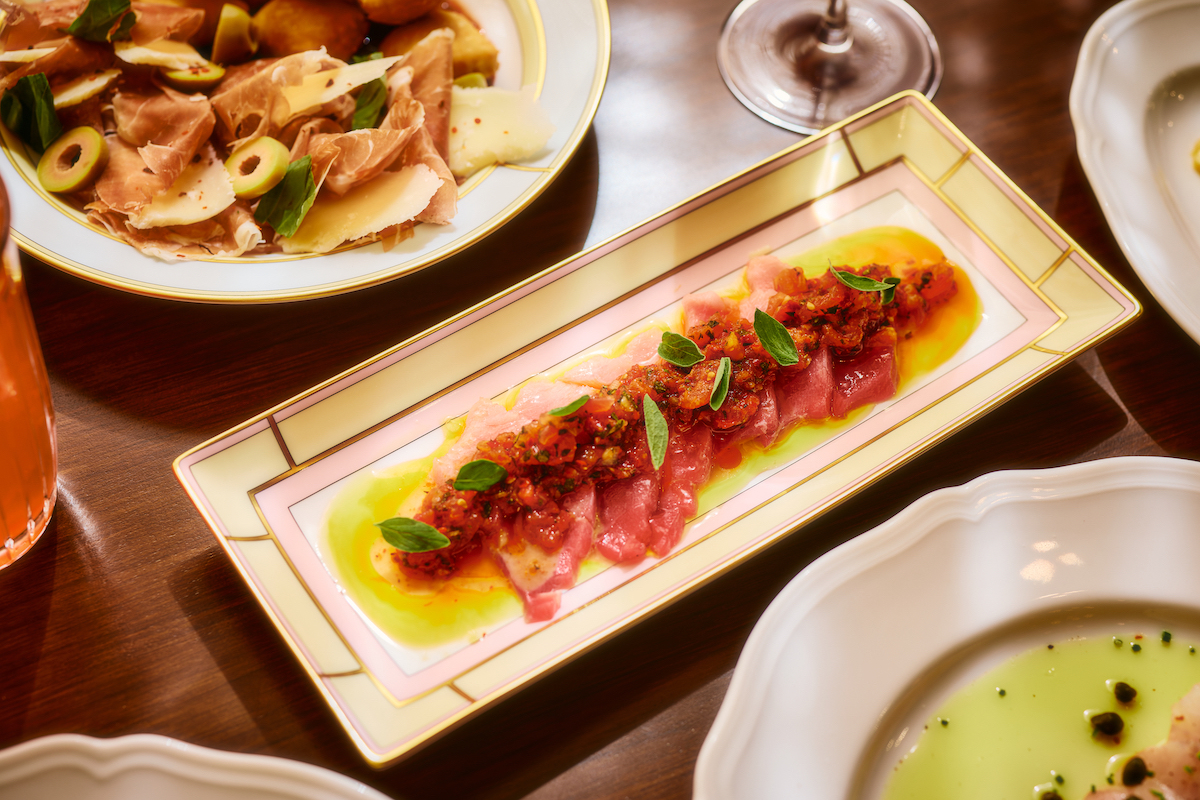 Toro crudo gets a colorful presentation with a bright, savory topping, olive oil, and fresh herbs. | Photo by Chase Hall