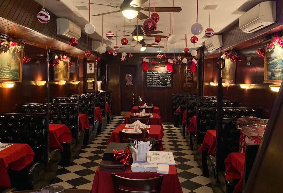 Cozy retro restaurant with red tablecloths, checkered floor, and holiday ornaments hanging from the ceiling.