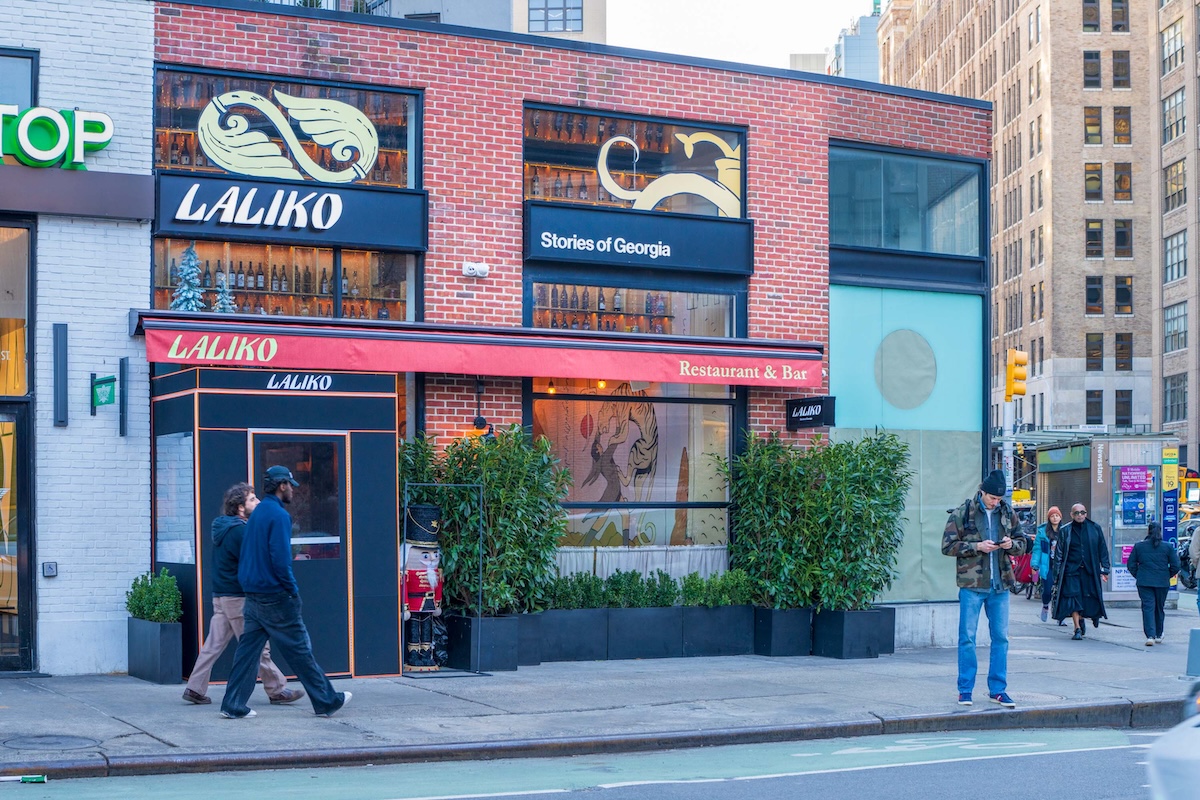 LaLiko Restaurant & Bar storefront on a brick building with a red awning and people walking by.