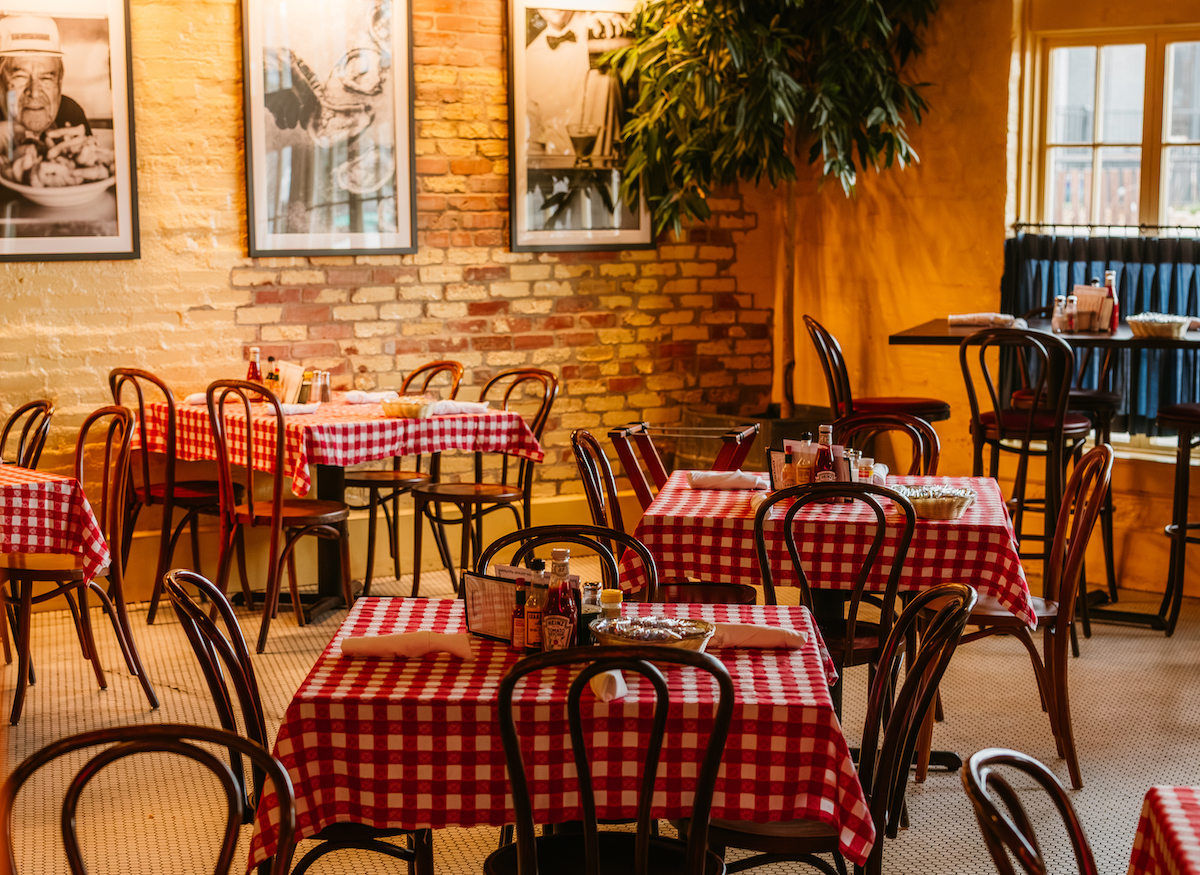 Red-and-white checkered tablecloths, exposed brick, and vintage photographs give S&D Oyster Company’s dining room its timeless, New Orleans-inspired charm. | Photo by S&D Oyster Company