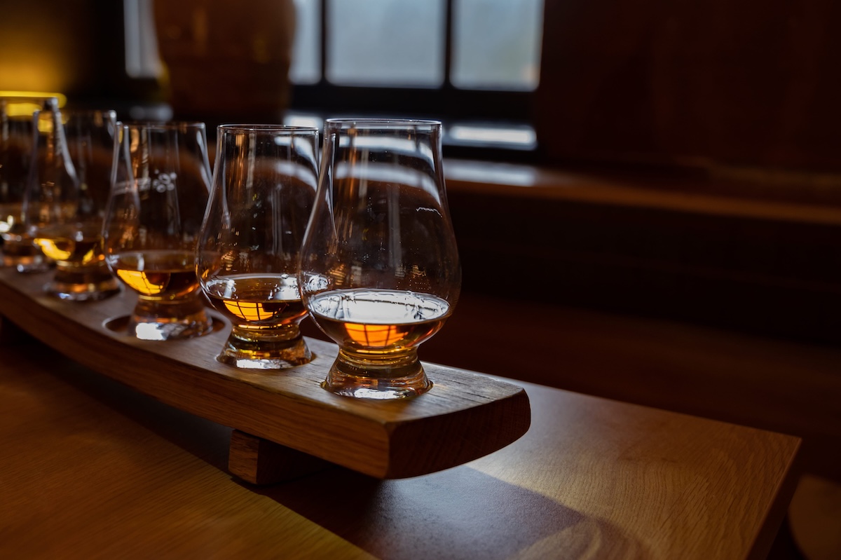 Flight of single malt scotch whiskey in glasses served in bar in Edinburgh, UK, tasting of dram of whiskey