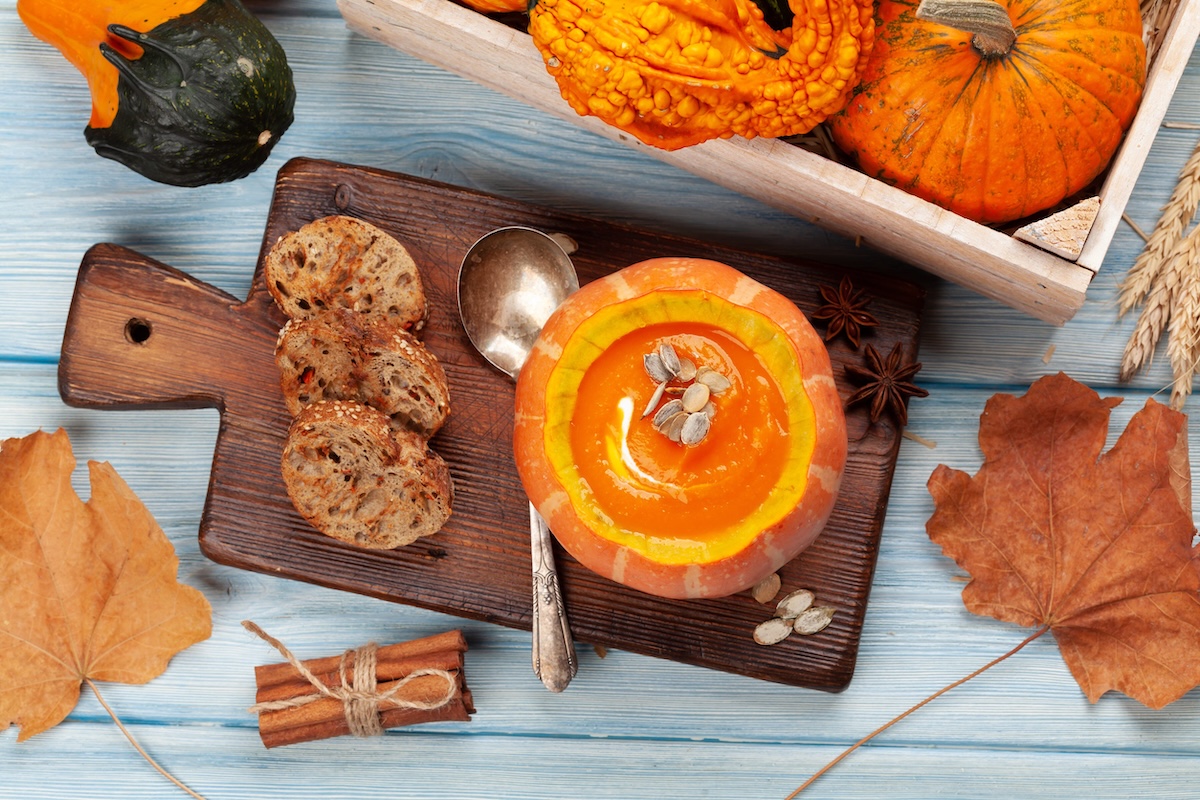 Pumpkin cream soup and various colorful squashes and pumpkins. Autumn vegetable harvest. Top view flat lay